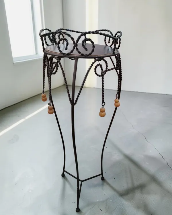 Mesa auxiliar de pie de hierro forjado con detalles decorativos