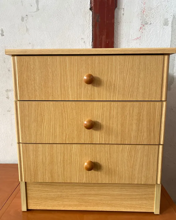 mesita de noche madera clara con tres cajones