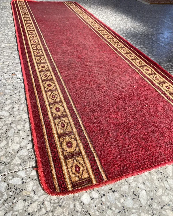 Alfombra de pasillo roja con bordes decorativos
