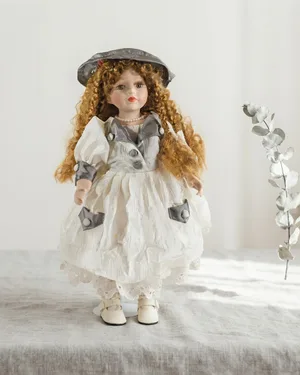 Muñeca de porcelana antigua con vestido blanco y gris - miniatura 1